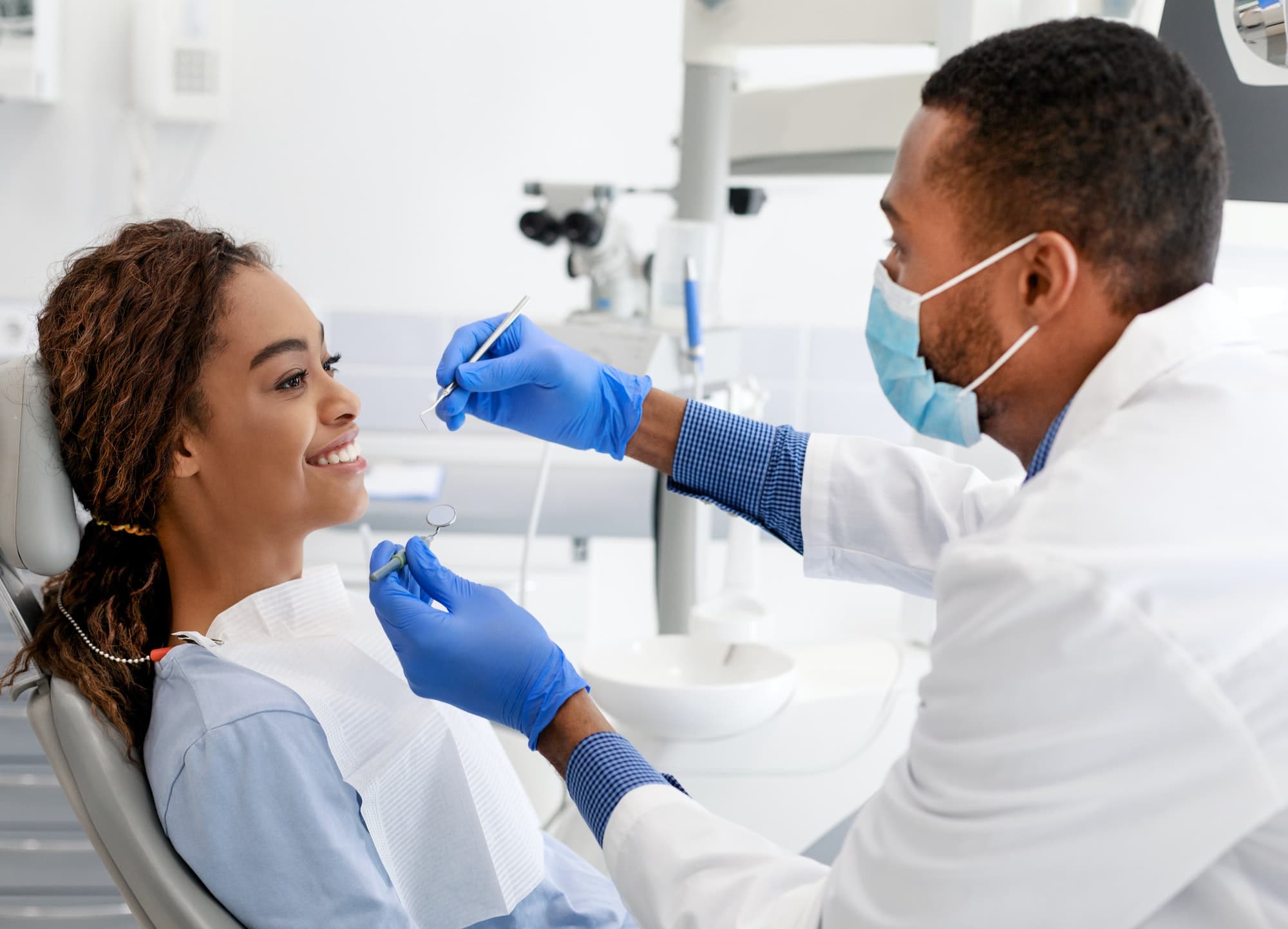 African lady smiling to doctor at dentist chair