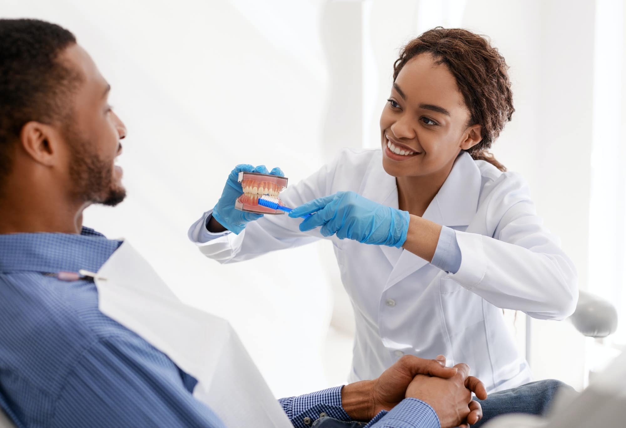 Dentist showing patient how to brush teeth in accurate way